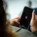 woman holding a smart phone and looking at a screen