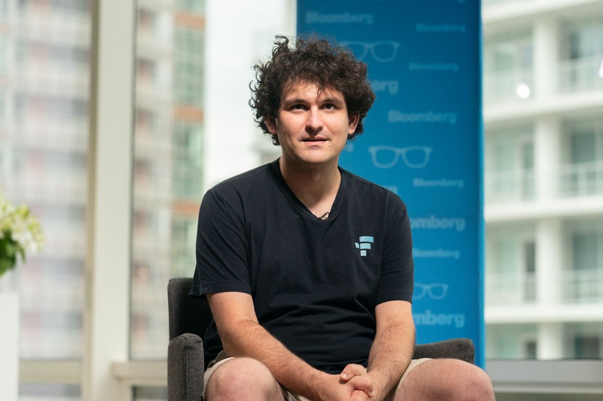 An image of SBF sittiing in a chair wearing a t-shirt and basketball shorts.