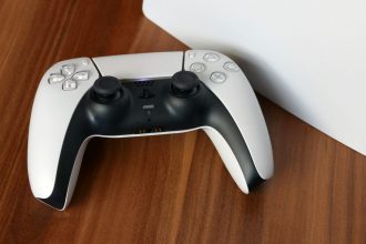 a white PlayStation 5 controller sitting on top of a white box
