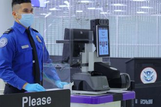 TSA agent standing next to facial recognition scanner