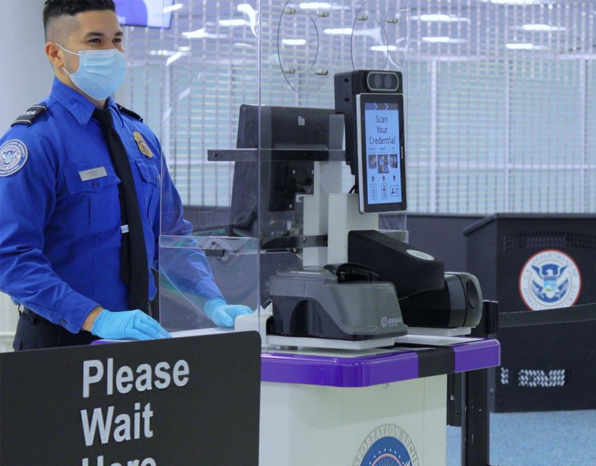 TSA agent standing next to facial recognition scanner