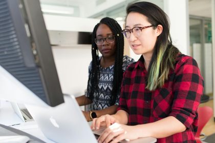 woman wearing red and black checkered blouse using macbook